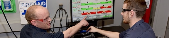 Two AIM students referencing a computer