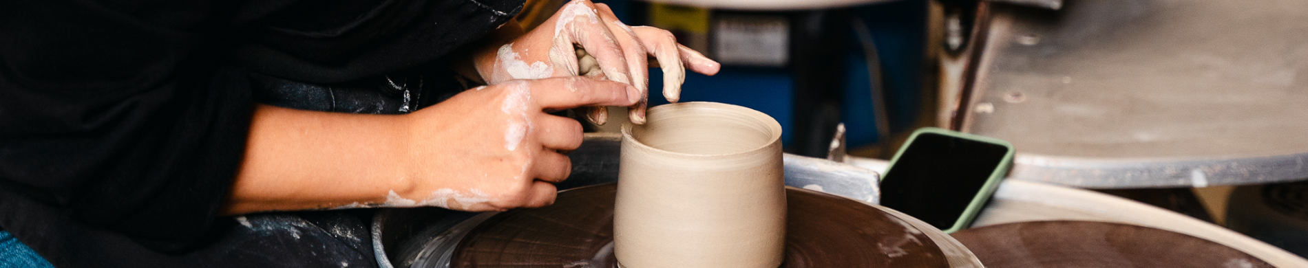 Student hand making pottery. 