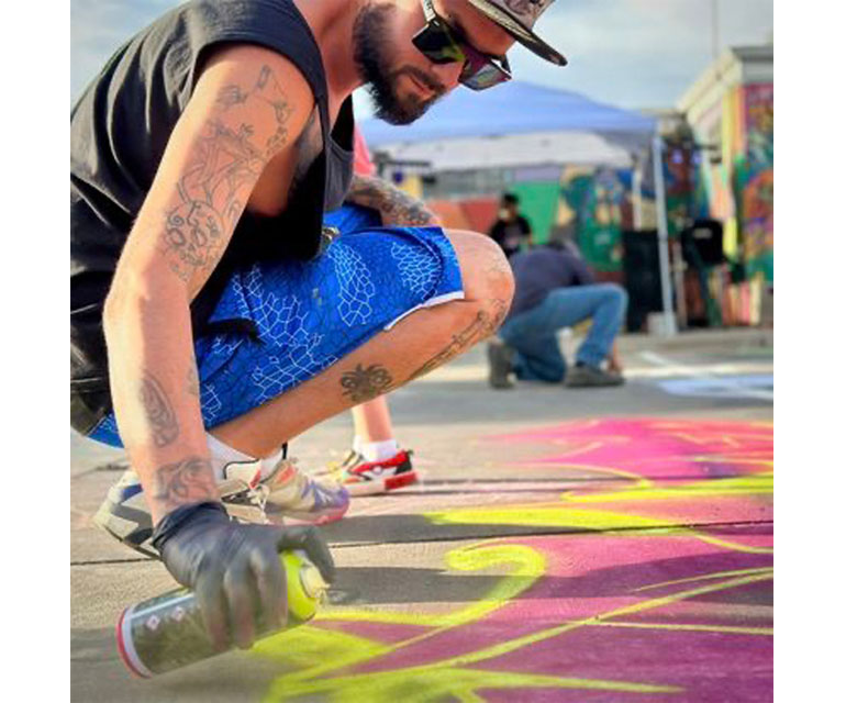 person spray painting the sidewalk