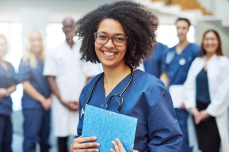 Woman smiling in scrubs with clipboard