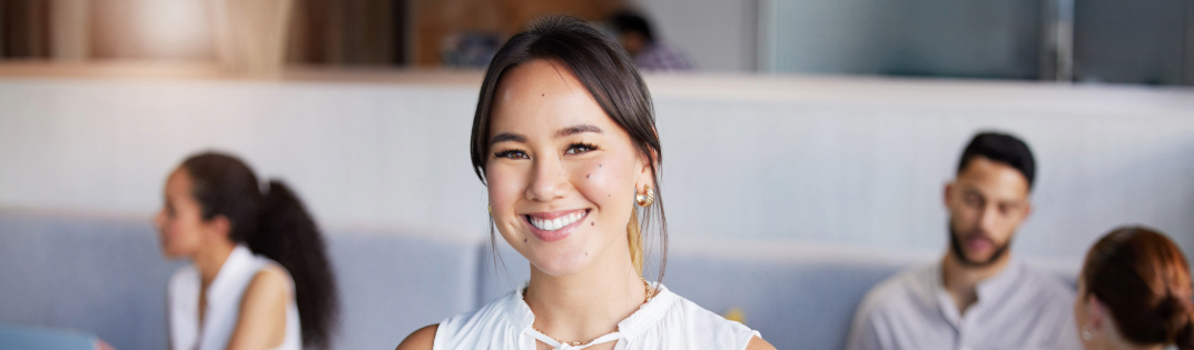 Women smiling at the camera with blurred people behind her in a building.