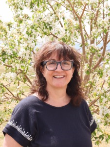Jenny Piazza smiling outside with the mountains behind her